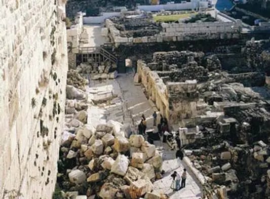 Aerial view of ancient stone ruins with weathered walls, scattered rubble, and archaeological excavation site